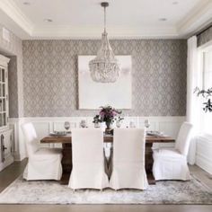 a dining room table with white chairs and a chandelier hanging from the ceiling