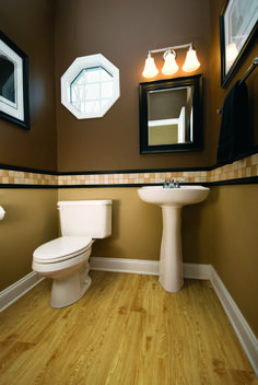 a bathroom with brown walls and white fixtures, including a toilet, sink, and mirror