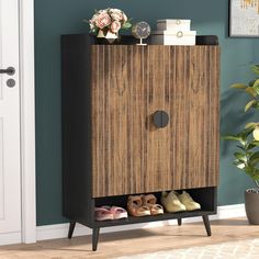 a wooden cabinet with shoes on it in front of a blue wall and potted plant