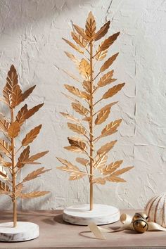 three gold leaves are on white plates and one is in the shape of a tree