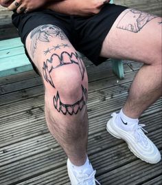 a man is sitting on a bench with his legs crossed and tattoos on the leg