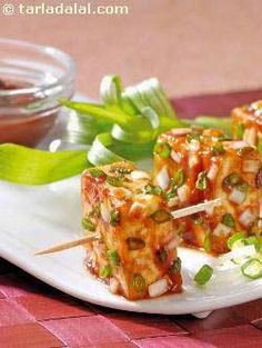 some food is sitting on a plate with toothpicks in it and garnished with green onions