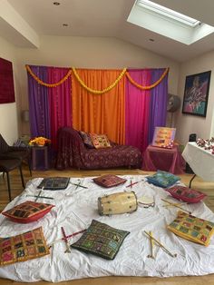 a bed room filled with lots of different types of pillows and blankets on top of a white sheet