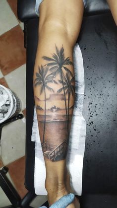 a man's arm with a palm tree and beach scene tattoo on the forearm