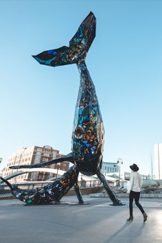 a woman is walking past a sculpture in the shape of a fish