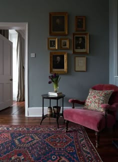 a living room with blue walls and pictures on the wall, including a pink chair