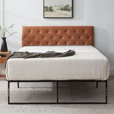 a bed with a brown headboard and foot board in a room next to a painting on the wall