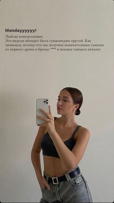 a woman taking a selfie with her cell phone in front of a white wall