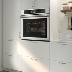 a white kitchen with an oven built into the wall