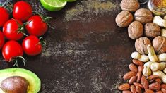 nuts, avocado, tomatoes, and other vegetables are arranged on a table