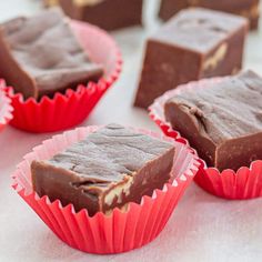 several pieces of chocolate fudge sitting on top of red paper wrappers next to each other