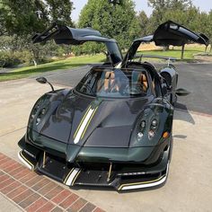 a black sports car parked on top of a parking lot next to a brick walkway