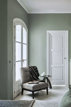 a bedroom with green walls and a chair in front of the door that leads to another room