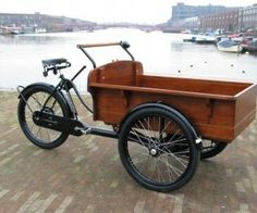 a bike with a wooden trailer attached to the back parked next to a body of water