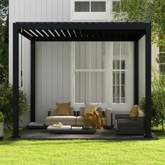 an outdoor living area with couches and tables in front of a white house on the grass