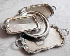 three silver trays sitting on top of a marble counter