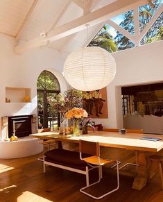 a dining room table with chairs and a lamp hanging from it's center point