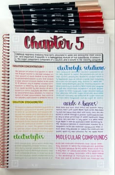 an open notebook with some writing on it next to four colored markers and pencils