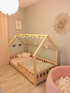 a child's room with a bed and ball pit in the floor, lights on