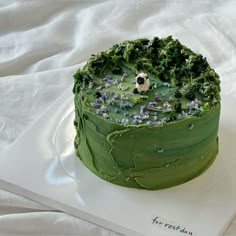 a cake with green frosting and purple flowers