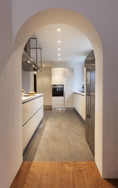 an archway leading into a kitchen with white cabinets and stainless steel appliances on the counters