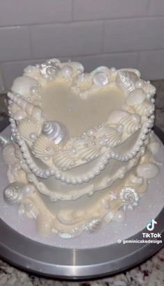 a heart shaped cake with seashells and pearls on it's sides is sitting on a silver platter