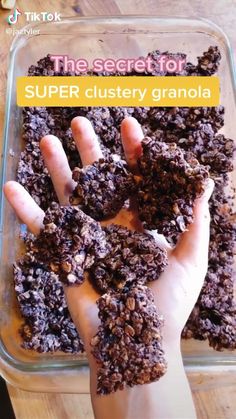 a person is reaching for some food in a glass dish on a wooden table with text overlay that reads the secret for super cluster granola