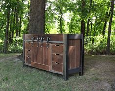 a wooden cabinet sitting in the middle of a field next to a tree and grass