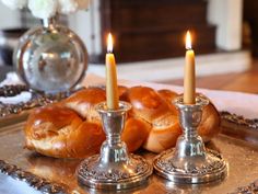 two silver candles are sitting on a tray