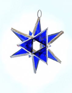 a blue glass star ornament hanging from a string on a white background,