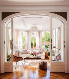 an open door leading into a living room with lots of furniture and flowers on the table