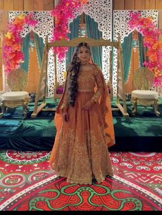 a woman standing in front of a mirror wearing an orange dress and long braids