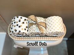 three rolls of toilet paper sitting on top of a white pedestal with gold polka dots