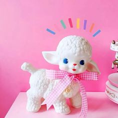 a white sheep figurine sitting on top of a table next to a bowl