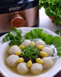 a white plate topped with dumplings and vegetables next to an instant pressure cooker