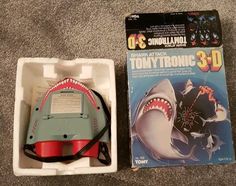 a box with a toy in it next to an open package for a shark trainer