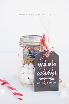 a jar filled with marshmallows next to a candy cane on top of a table