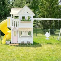 a play house with a slide and swing set in the back yard for children to play