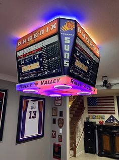 a basketball scoreboard hanging from the ceiling in a room with pictures on the wall