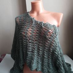 a mannequin wearing a green knitted shawl with holes in the middle