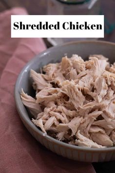 shredded chicken in a bowl on top of a pink table cloth with the words shredded chicken