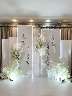 two tall white flower arrangements sitting on top of a table next to candles and signs