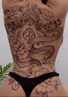 the back of a woman's body with tattoos on her stomach and an image of a snake