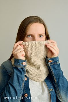 a woman covering her face with a knitted cowgirl neck scarf in front of her