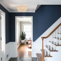 an entryway with blue walls and white trim on the stairs is flanked by a wooden banister