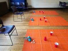 two rows of chairs with cups on the floor in front of them, and one chair is empty