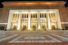 the front entrance of a large building lit up at night with lights on it's sides