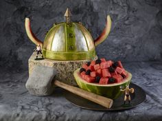 a watermelon bowl filled with blackberries next to a helmet on top of it