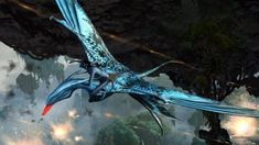 a blue bird flying through the air next to trees and rocks with fire coming out of it's wings