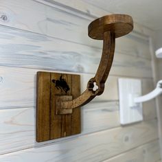 a wooden light fixture mounted to the side of a white painted wood paneled wall